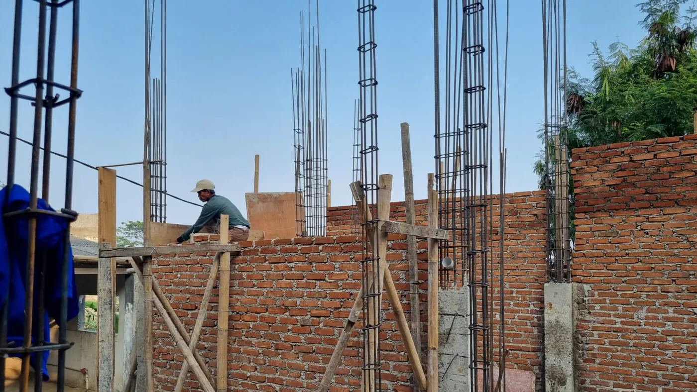 Pekerja memasang bata merah pada dinding Rumah Tahfidz Darul Ihsan yang sedang dibangun